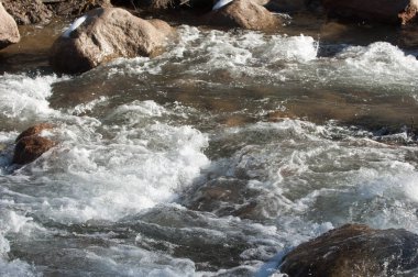 su küçük bir nehir erken ilkbahar akarsu. Bahar sahne. donmuş bir dere ile dağ manzarası