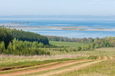 Bahar, büyük bir nehir, renkli ağaçlar. Nehir kenarında yumuşak sabah şafak ışığı içinde filizlenen büyük ağaç. Sakin nehir düşük dağlara akan
