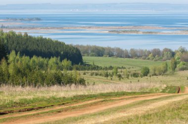Bahar, büyük bir nehir, renkli ağaçlar. Nehir kenarında yumuşak sabah şafak ışığı içinde filizlenen büyük ağaç. Sakin nehir düşük dağlara akan