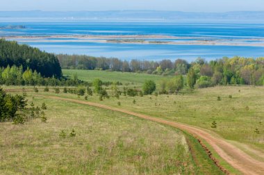 Bahar günü ülkede yol. Köy yolunda bahar günü ormanında. Köy yolunda yaz, yeşil alan ve mavi temiz gökyüzü arasında. Doğa kavramsal görüntü.