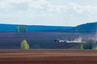 Alan sürülmüş, ekilen hububat. Bahar günü sürülmüş alana. Siyah toprak sürülmüş alan. Mavi gökyüzünde sürülmüş alan