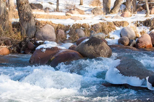 su küçük bir nehir erken ilkbahar akarsu. Bahar sahne. donmuş bir dere ile dağ manzarası
