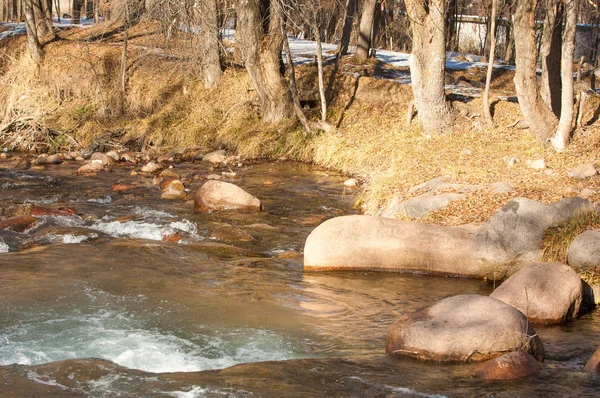 su küçük bir nehir erken ilkbahar akarsu. Bahar sahne. donmuş bir dere ile dağ manzarası