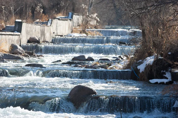 su küçük bir nehir erken ilkbahar akarsu. Bahar sahne. donmuş bir dere ile dağ manzarası