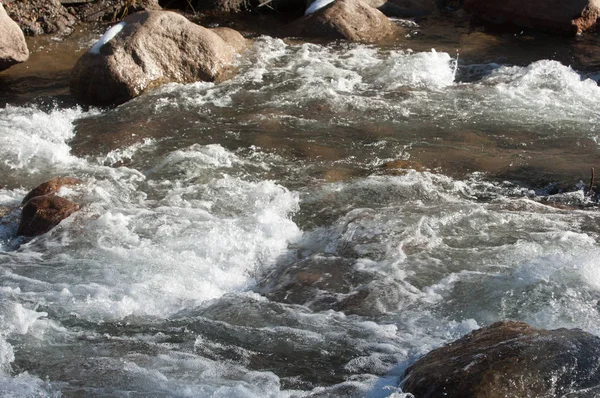 su küçük bir nehir erken ilkbahar akarsu. Bahar sahne. donmuş bir dere ile dağ manzarası