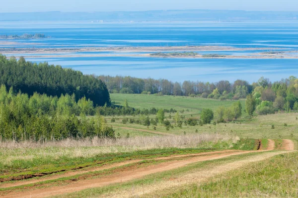 Bahar günü ülkede yol. Köy yolunda bahar günü ormanında. Köy yolunda yaz, yeşil alan ve mavi temiz gökyüzü arasında. Doğa kavramsal görüntü.