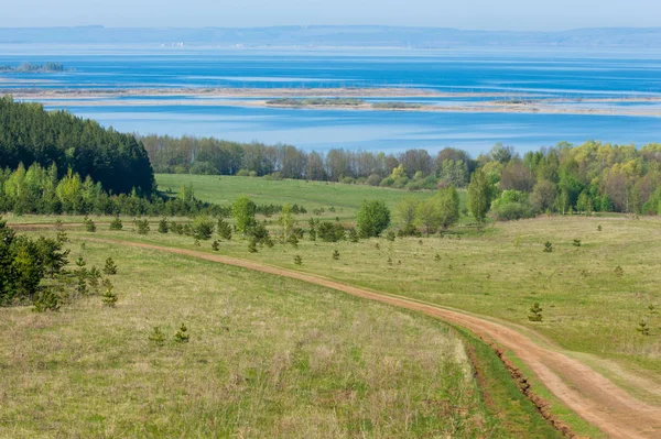 Bahar günü ülkede yol. Köy yolunda bahar günü ormanında. Köy yolunda yaz, yeşil alan ve mavi temiz gökyüzü arasında. Doğa kavramsal görüntü.