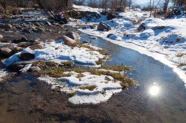 su küçük bir nehir erken ilkbahar akarsu. Bahar sahne. donmuş bir dere ile dağ manzarası