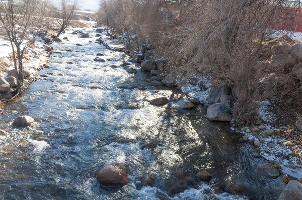 su küçük bir nehir erken ilkbahar akarsu. Bahar sahne. donmuş bir dere ile dağ manzarası
