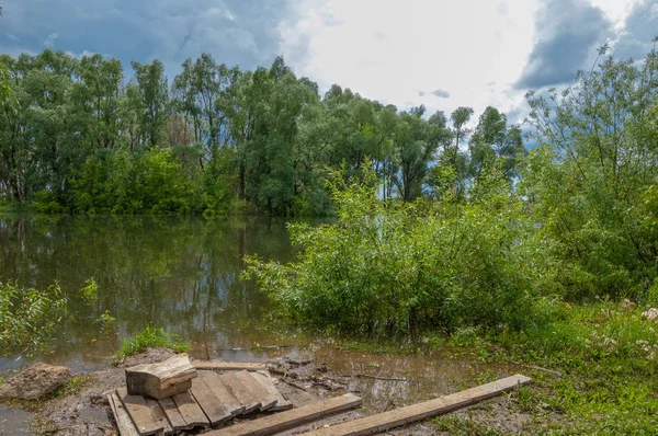 floodwaters. water overflowing as the result of a flood.  High spring water. A sunny day in the beginning of spring on the river.  Heaven with the clouds. Spring landscape. Spring is coming.