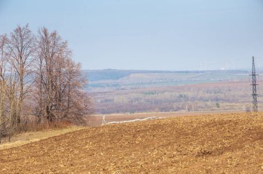 Bahar manzara. Taze sürülmüş alan. engebeli arazi. ağaçların yaprakları olmadan. Çok renkli bahar ağaçları. Geçen yılki kış kar kalan. Son kar.