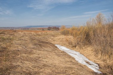 Bahar manzara. Taze sürülmüş alan. engebeli arazi. ağaçların yaprakları olmadan. Çok renkli bahar ağaçları. Geçen yılki kış kar kalan. Son kar.