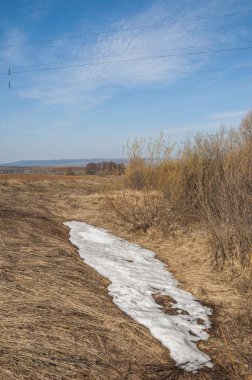 Bahar manzara. Taze sürülmüş alan. engebeli arazi. ağaçların yaprakları olmadan. Çok renkli bahar ağaçları. Geçen yılki kış kar kalan. Son kar.