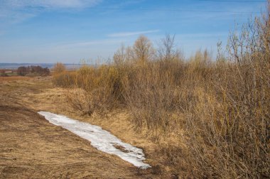 Bahar manzara. Taze sürülmüş alan. engebeli arazi. ağaçların yaprakları olmadan. Çok renkli bahar ağaçları. Geçen yılki kış kar kalan. Son kar.