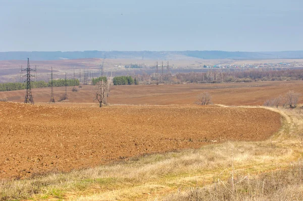 Bahar manzara. Taze sürülmüş alan. engebeli arazi. ağaçların yaprakları olmadan. Çok renkli bahar ağaçları. Geçen yılki kış kar kalan. Son kar.