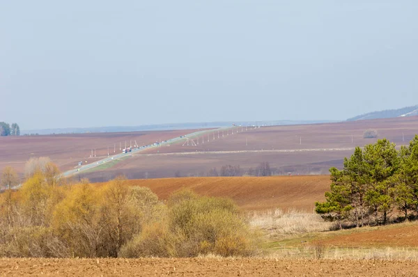 Bahar manzara. Taze sürülmüş alan. engebeli arazi. ağaçların yaprakları olmadan. Çok renkli bahar ağaçları. Geçen yılki kış kar kalan. Son kar.