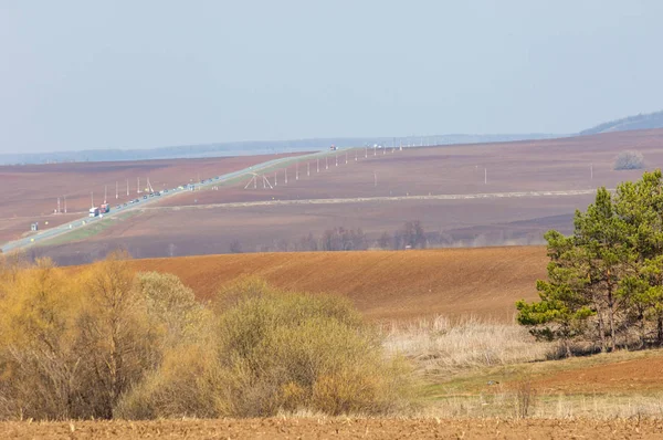Bahar manzara. Taze sürülmüş alan. engebeli arazi. ağaçların yaprakları olmadan. Çok renkli bahar ağaçları. Geçen yılki kış kar kalan. Son kar.