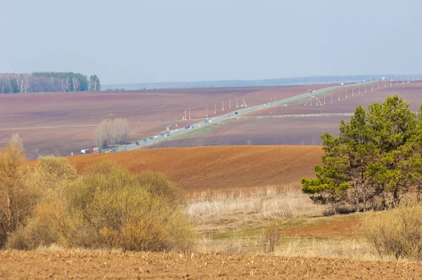 Bahar manzara. Taze sürülmüş alan. engebeli arazi. ağaçların yaprakları olmadan. Çok renkli bahar ağaçları. Geçen yılki kış kar kalan. Son kar.