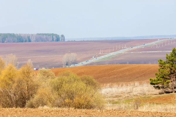 Bahar manzara. Taze sürülmüş alan. engebeli arazi. ağaçların yaprakları olmadan. Çok renkli bahar ağaçları. Geçen yılki kış kar kalan. Son kar.