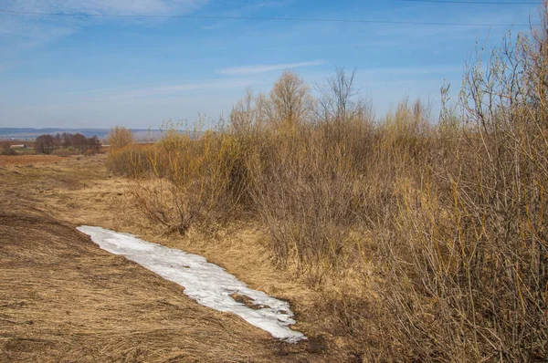 Bahar manzara. Taze sürülmüş alan. engebeli arazi. ağaçların yaprakları olmadan. Çok renkli bahar ağaçları. Geçen yılki kış kar kalan. Son kar.