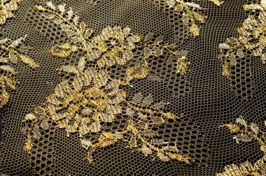 Resmi doku arka planı, dekoratif altın dantel desenli. Altın vintage dantelli arka plan. Siyah bir zemin üzerine altın dantel. Spandex, makro. Dantelli dekoratif çiçek desenli.
