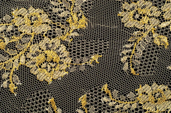 Image texture background, decorative gold lace with pattern. Golden vintage lacy background. Golden lace on a black background. Spandex, macro. Lacy decorative floral pattern.