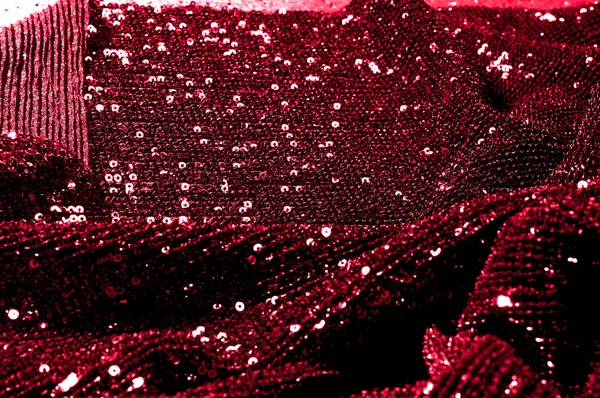 Texture, background, pattern, red fabric with paillettes. Look at these neon red sequins. Round neon pink sparkles glitter overlapping iridescent glitter on a clean purple grid.