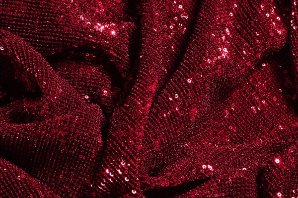 Texture, background, pattern, red fabric with paillettes. Look at these neon red sequins. Round neon pink sparkles glitter overlapping iridescent glitter on a clean purple grid.