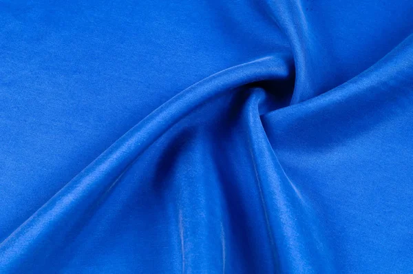 Background texture, pattern. Thick thick silk fabric of blue color. Add a touch of luxury to any design, building it with this super-heavy and very dense polyester fabric.