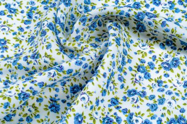 Arka plan doku, desen. küçük mavi çiçekler ile ince pamuklu kumaş. Kumaş zeytin yeşil çiçek sapları ve küçük mavi - aqua çiçek karışımı olan beyaz bir arka plana sahiptir. 