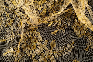Resmi doku arka planı, dekoratif altın dantel desenli. Altın vintage dantelli arka plan. Siyah bir zemin üzerine altın dantel. Spandex, makro. Dantelli dekoratif çiçek desenli.