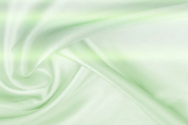 Background pattern, texture. Silk fabric of green tones. Fine silk - top view - close-up of a thin silk surface shadow color serenity - pastel tone.