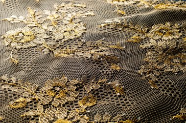 Resmi doku arka planı, dekoratif altın dantel desenli. Altın vintage dantelli arka plan. Siyah bir zemin üzerine altın dantel. Spandex, makro. Dantelli dekoratif çiçek desenli.