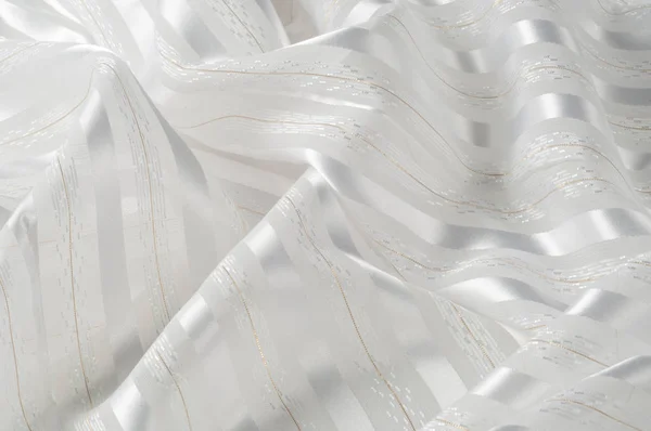 Background texture, pattern. White silk fabric, with a light strip. Closeup of rippled white silk fabric. Smooth elegant golden silk can use as wedding background.  Retro style