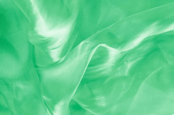 Background texture, pattern. Green silk background with some soft folds and highlights. green background abstract cloth or liquid wave illustration of wavy folds of silk texture satin