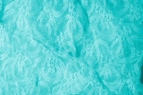 Texture, fabric, background. Lacy turquoise fabric, lace. A thin open fabric, usually cotton or silk, made by a loop, twisting or knitting on patterns and is used specially for trimming clothes.