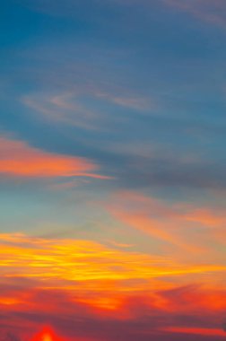 Bulutlu, güneşli, gün batımlı, batan güneşin turuncu-sarı tonlarıyla gökyüzünün fotoğrafı.