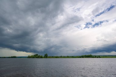Yaz fotoğrafı, güçlü gök gürültülü bulutlar, mavi gökyüzü, karanlık keskin su, Kama Nehri boyunca turist yürüyüşü.