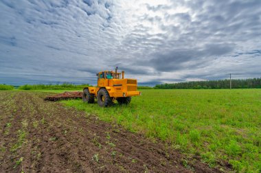 Bahar fotoğrafçılığı, ziraat makineleriyle manzara, bir traktör tarlayı sürüyor, tarlayı sürüyor, kuşlar ekilebilir arazinin üzerinde uçuyor.