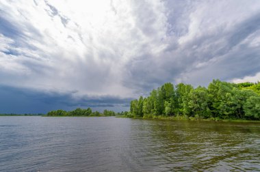 Yaz fotoğrafı, güçlü gök gürültülü bulutlar, mavi gökyüzü, karanlık keskin su, Kama Nehri boyunca turist yürüyüşü.