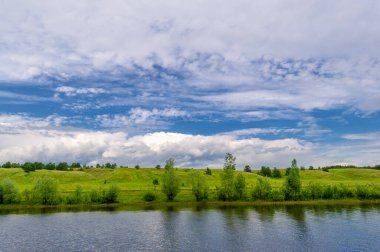 Yaz fotoğrafı, güçlü gök gürültülü bulutlar, mavi gökyüzü, karanlık keskin su, Kama Nehri boyunca turist yürüyüşü.