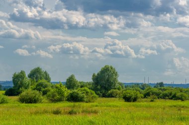 Yaz manzarası, gök gürültülü bulutlar, mavi gökyüzü, sel basmış çayır tarlaları, yaz renklerinin kokusu ve çeşitli kır çiçekleri.