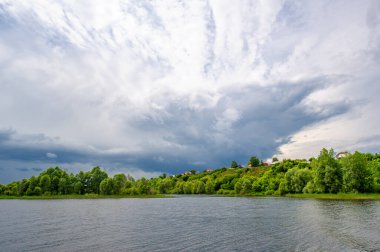 Yaz fotoğrafı, güçlü gök gürültülü bulutlar, mavi gökyüzü, karanlık keskin su, Kama Nehri boyunca turist yürüyüşü.