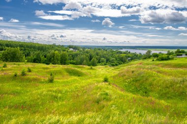 Yaz manzarası, büyük bir nehir, nehrin kıyısında çayır çiçekleri, gökyüzünde güçlü bulutlar, Kama Nehri boyunca bir turist yürüyüşü.
