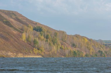 Sonbahar manzarası, koyu mavi su, son sıcak günler, nehir, ağaçlar, rüzgarlı hava, sarı-kırmızı sonbahar yaprakları.
