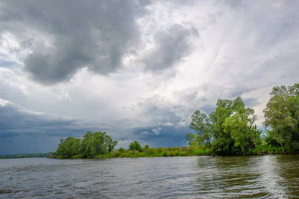 Yaz fotoğrafı, güçlü gök gürültülü bulutlar, mavi gökyüzü, karanlık keskin su, Kama Nehri boyunca turist yürüyüşü.