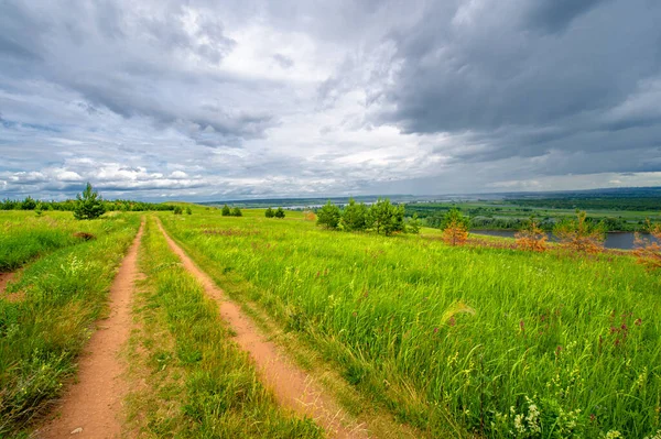 Yaz manzarası, büyük bir nehir, nehrin kıyısında çayır çiçekleri, gökyüzünde güçlü bulutlar, Kama Nehri boyunca bir turist yürüyüşü.
