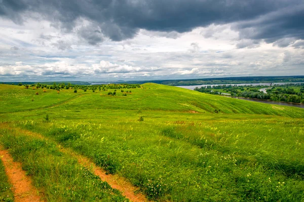 Yaz manzarası, büyük bir nehir, nehrin kıyısında çayır çiçekleri, gökyüzünde güçlü bulutlar, Kama Nehri boyunca bir turist yürüyüşü.