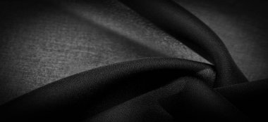 Arkaplan dokusu koyu siyah şifon ipeği yumuşak şeffaf bir kumaştır ve pürüzlüdür (matte, creped) çünkü bükülmüş iplik kullanımı.
