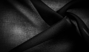 Arkaplan dokusu koyu siyah şifon ipeği yumuşak şeffaf bir kumaştır ve pürüzlüdür (matte, creped) çünkü bükülmüş iplik kullanımı.